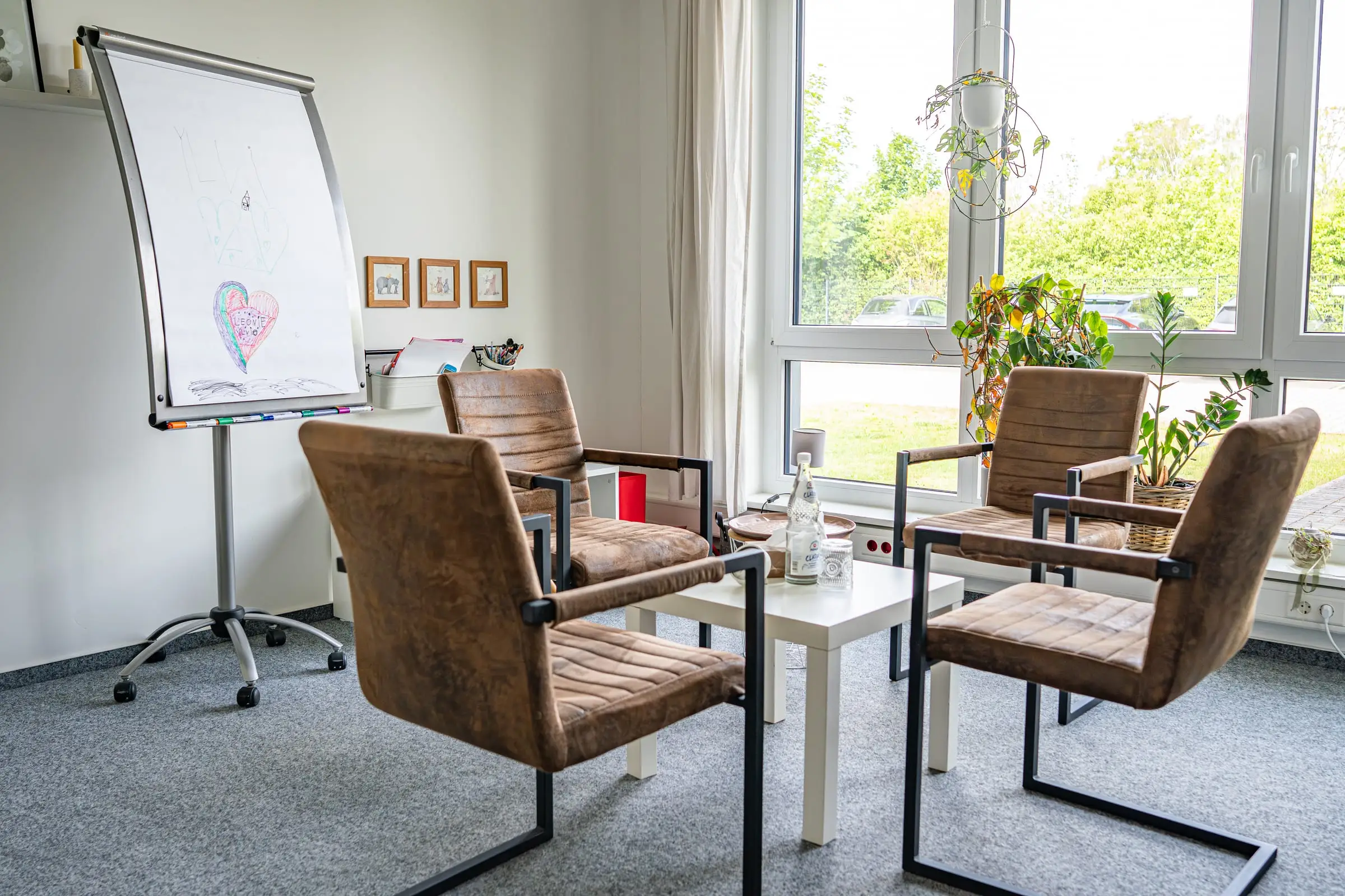 Seminarraum der Praxis JUNA mit Sitzgruppe und Flipchart